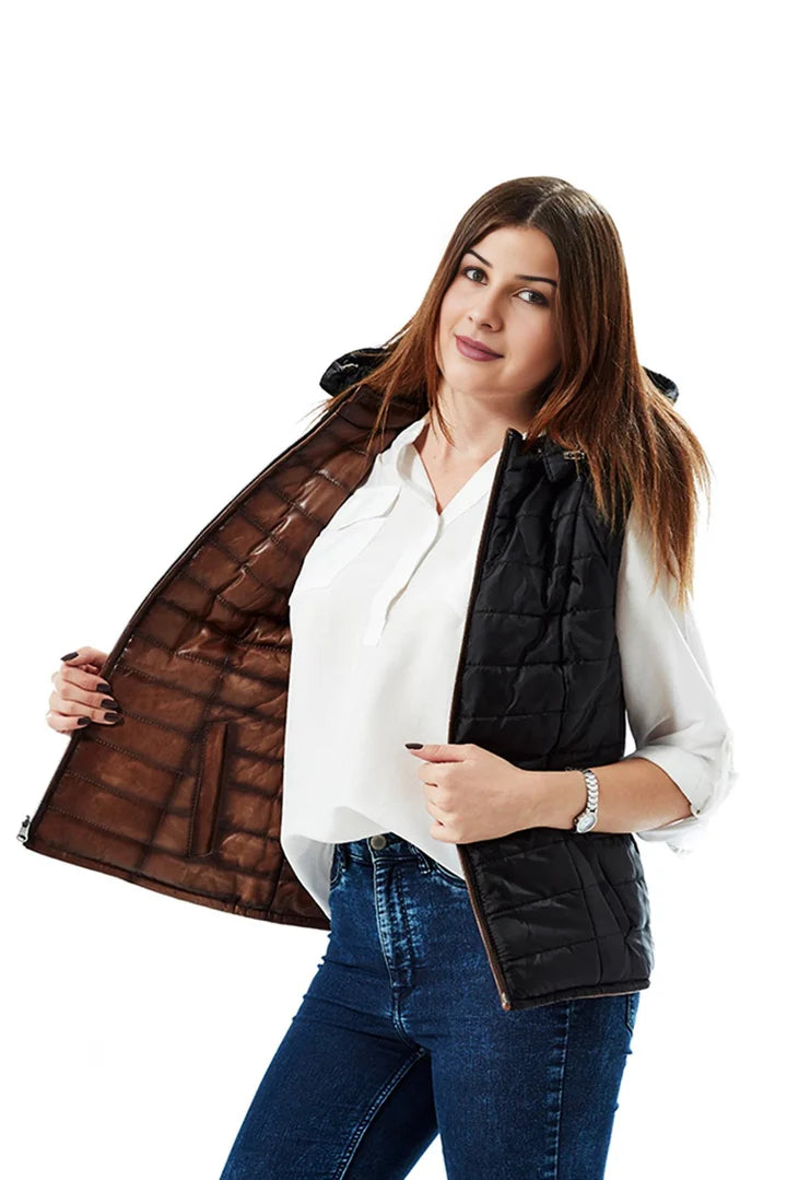 Woman wearing a black puffer vest over a white shirt and blue jeans on a white background